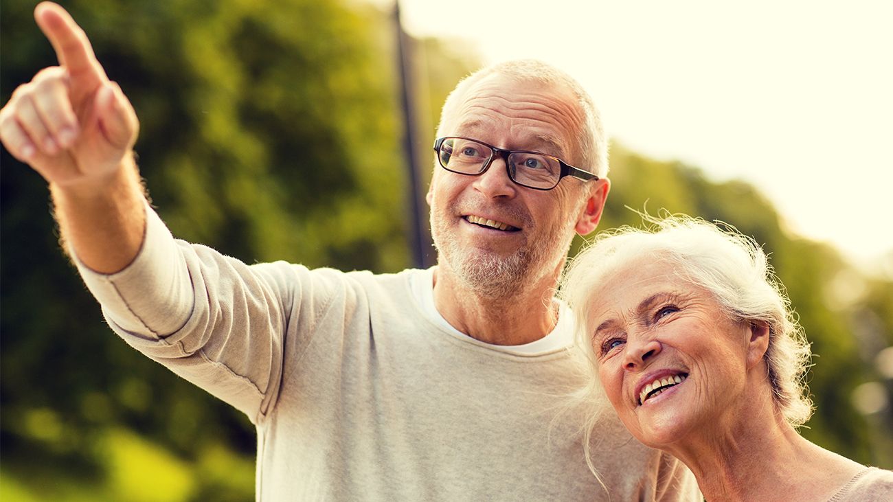 Senior man pointing with his wife to a home